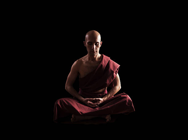buddhistischer mönch in meditation pose über schwarzem hintergrund - tibetan culture stock-fotos und bilder