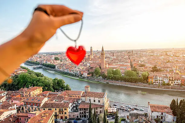 Holding decoration in the form of heart on the italian town Verona background. Verona is famous city of love in the north of Italy.