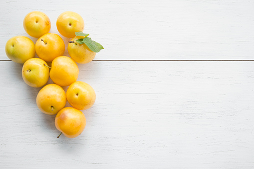 yellow plum fruit on white wooden table