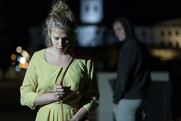 Criminal observing young woman Criminal observing young woman walking alone at night man holding gun at night in the city stock pictures, royalty-free photos & images