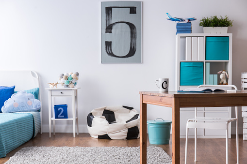 Stylish boy's room with wooden desk and pillow in football ball shape