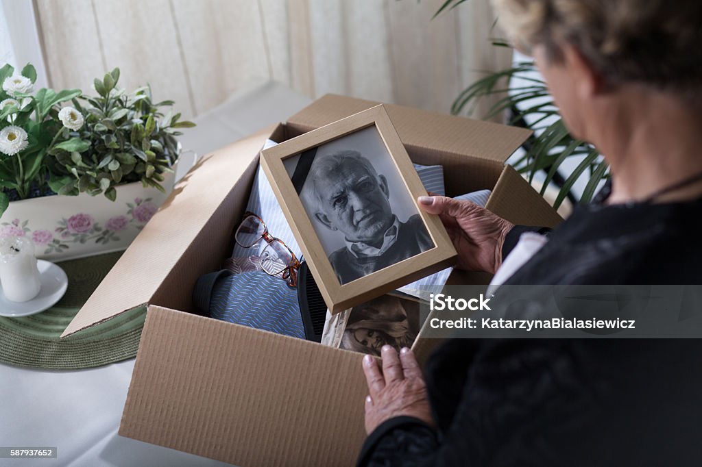 Last look on husband Woman is packing things of her dead husband Photograph Stock Photo