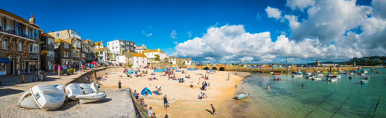 Crowds of holiday makers, day trippers and tourists enjoying the summer sunshine on the popular harbour beach of St. Ives, Cornwall.