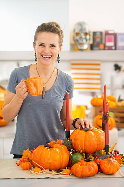 istock Smiling woman having hot beverage in Halloween decorated kitchen 587941892