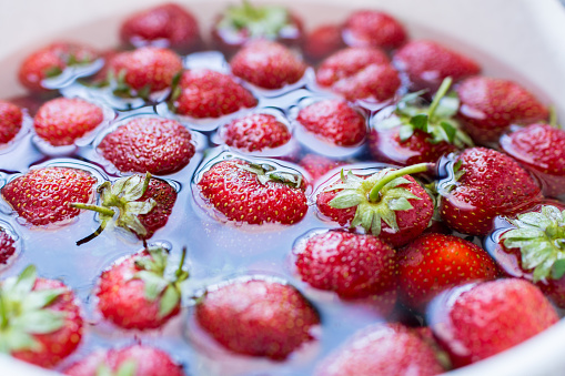 Strawberries soaked in water, organic food preparation, close-up