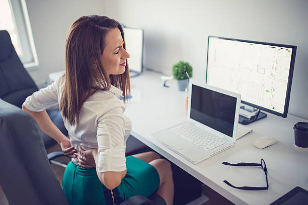 Pain Young woman having back pain while sitting at desk in office acute angle photos stock pictures, royalty-free photos & images