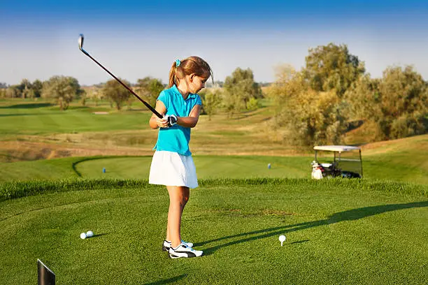 Photo of Cute little girl playing golf on a field outdoor