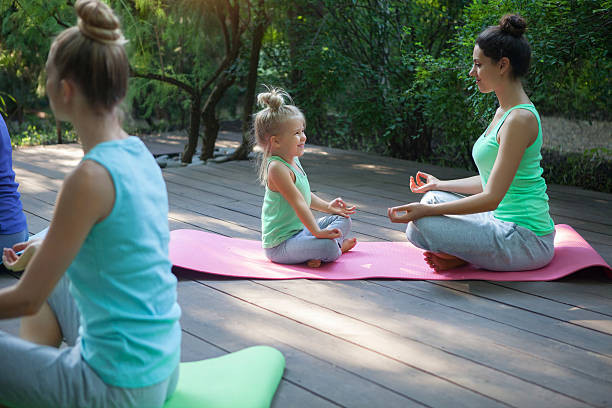 istock Group of mothers and daughters doing exercise practicing yoga ou 587946930