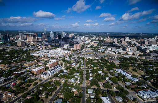 Dramatic Perspective Over East Austin Texas Aerial Cityscape over East side looking west with the Texas Hill Country background behind the Skyline of the Capital City on a spotted clouded Blue Sky morning Perfect amazing view of Central Texas Crown City