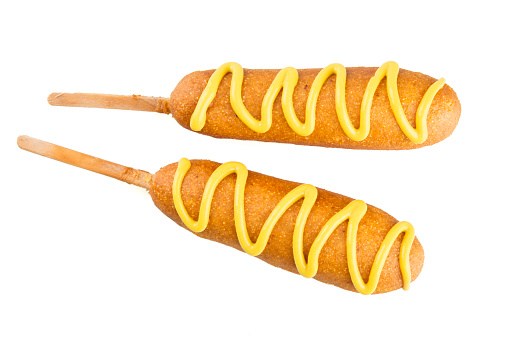 Two corn dogs isolated on white topped with mustard