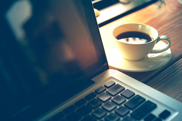 istock white Cup of coffee and laptop on wooden table. 587956514