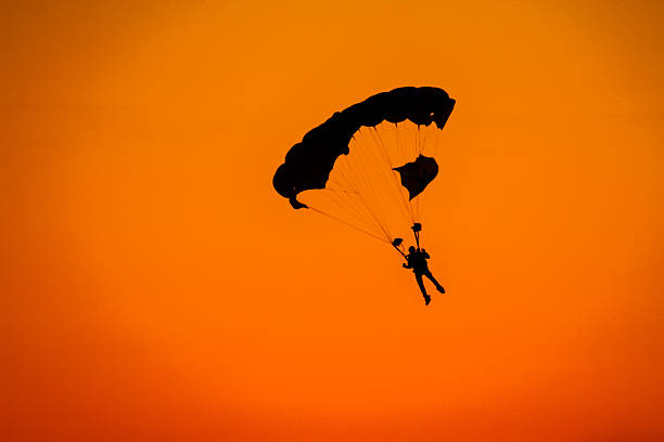 Man parachuting off a plane into the sunset