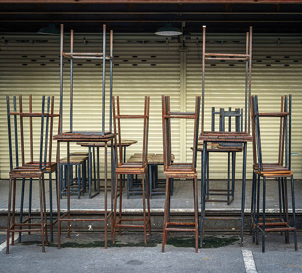 Stacked tables and chairs in front of closed store stock photo