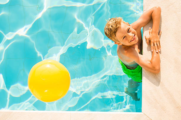 garçon (9 ans) jouant avec le beach ball en piscine - beach ball swimming pool ball child photos et images de collection