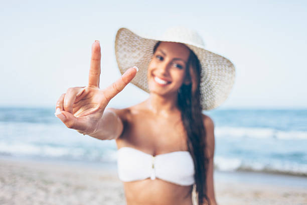 istock Smiling young woman making peace sign on beach 588242994