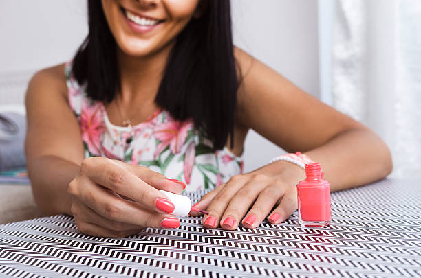 jeune femme appliquant du vernis à ongles sur son ongle - coral break photos et images de collection