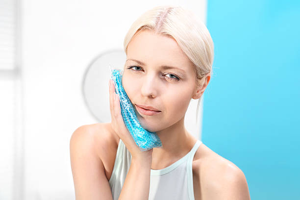 Toothache. Compress analgesic. Woman puts a cold compress useful for toothache.  ice pack photos stock pictures, royalty-free photos & images