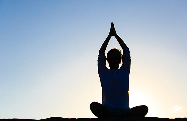 istock silhouette of young man doing yoga at sunset 588260780