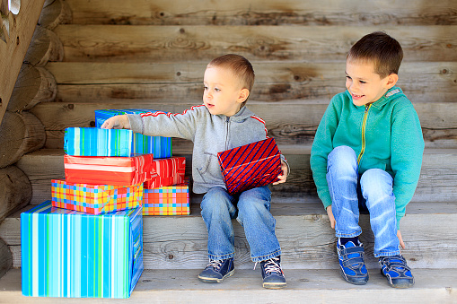 two cute boys sitting on the steps with gifts and look forward to unwrapping presents. the concept of happy holidays. christmas