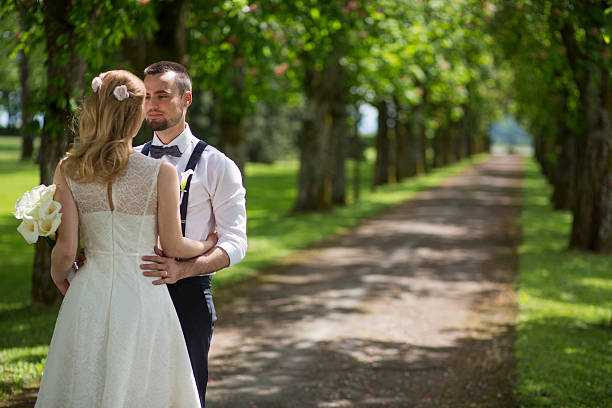 istock Bride and groom standing in park 588264352