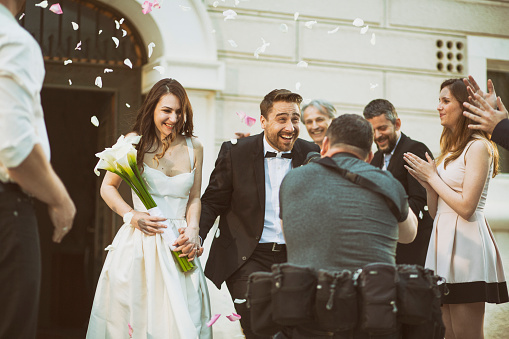 Photographer taking picture of bride and groom as they leave church.