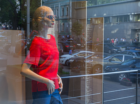 Female mannequin in the window and a reflection of the city