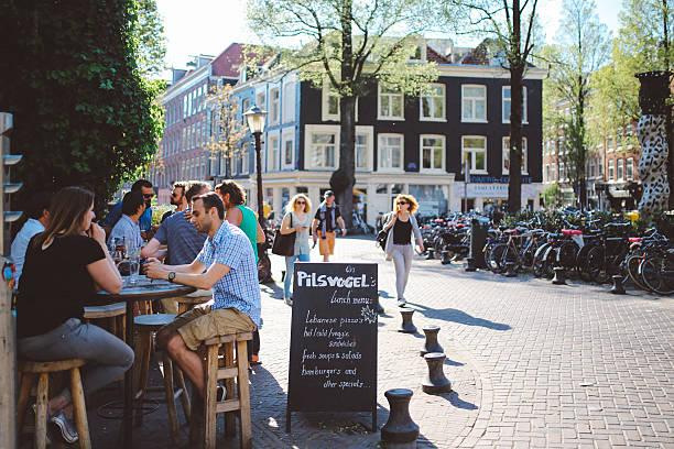 Amsterdam, The Netherlands - May 8, 2016: People sitting, talking, drinking in the cafe in Amsterdam near Leidseplein on a bright summer day, enjoying their free time. 