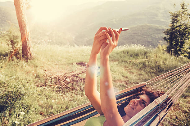 Tourist taking selfie Young woman in a hammock taking selfie hammock relaxation women front or back yard stock pictures, royalty-free photos & images