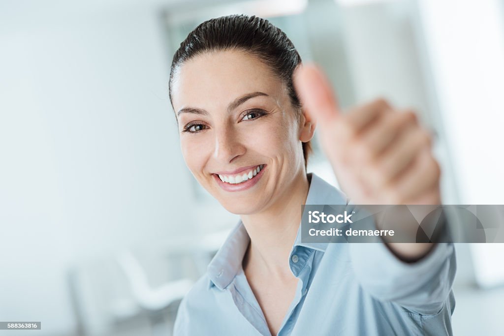 Beautiful businesswoman thumbs up Beautiful businesswoman thumbs up smiling at camera, success and achievement concept Achievement Stock Photo