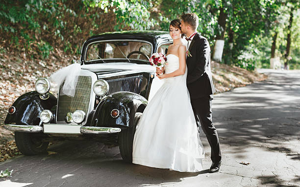 istock Bridegroom and bride standing near retro wedding car 588365024