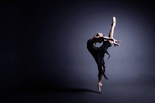 young ballerina in a black suit is dancing in dark - bale imagens e fotografias de stock