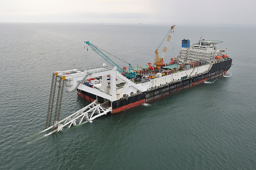 Loading grain into sea cargo vessel in commercial port from trucks.
