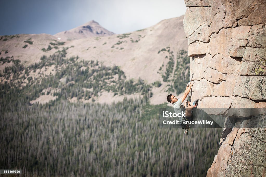 Asian Man Rock Climbing David Trac climbs a steep wall in the Uinita Mountains of Utah, USA.  Adrenaline Stock Photo