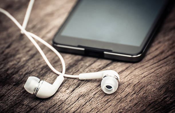 istock Smart phone with headphones lay on wooden table 588373882