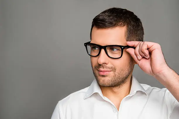Photo of Smart man  touching his glasses and looking ahead