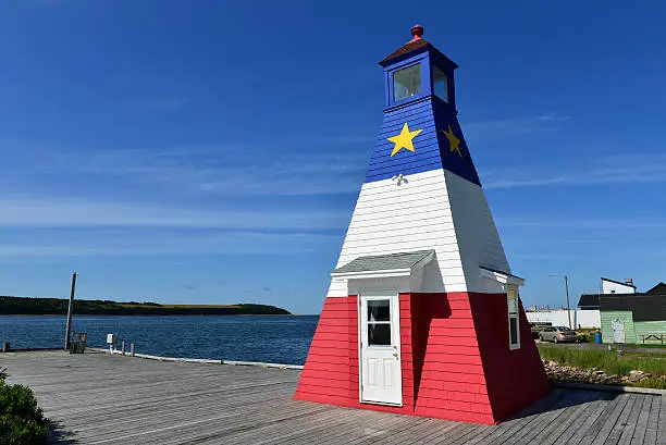 The iconic Cheticamp Harbour Lighthouise painted in the design of the Acadian flag on the Cabot Trail in Cape Breton, Nova Scotia, Canada