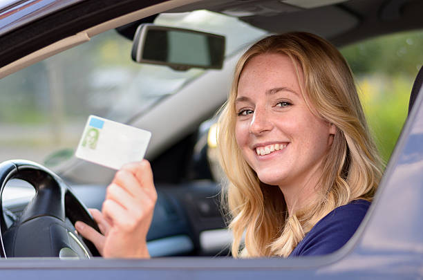 istock Happy young woman showing off her drivers license 588381682