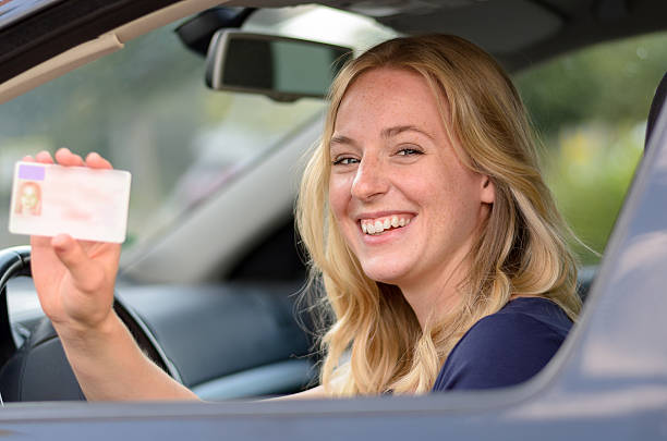 istock Happy young woman showing off her drivers license 588381696