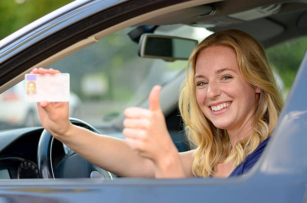 istock Young blond woman showing off her drivers license 588381714