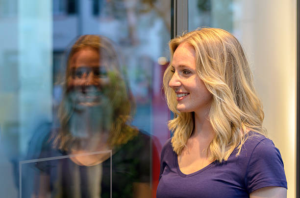 istock Smiling young woman reflected in a store window 588381960