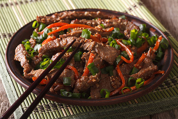 istock Asian cuisine: slices of beef fried with sesame and carrot 588381996