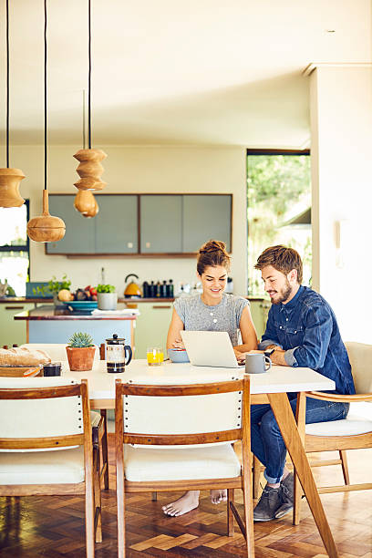 Happy male and female hipsters using laptop at dining table