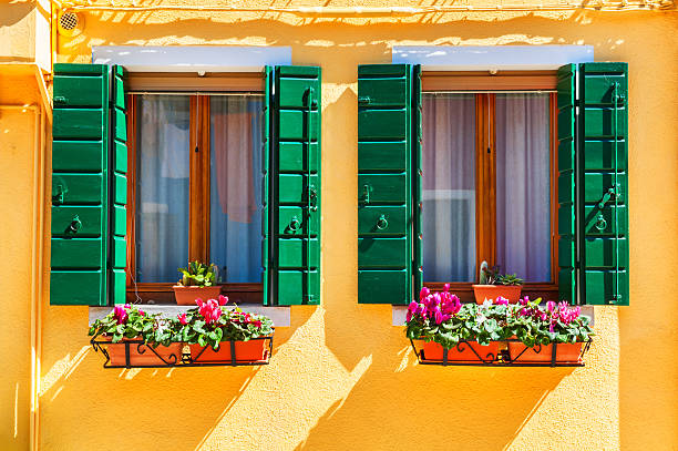 istock Yellow house and window with green shutters 588385590