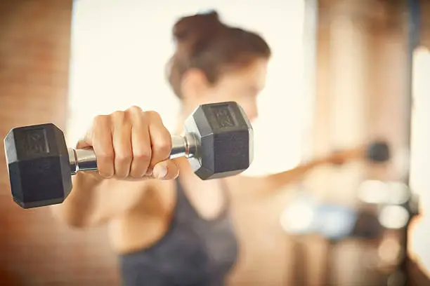 Photo of Close-up of dumbbell held by young woman in gym