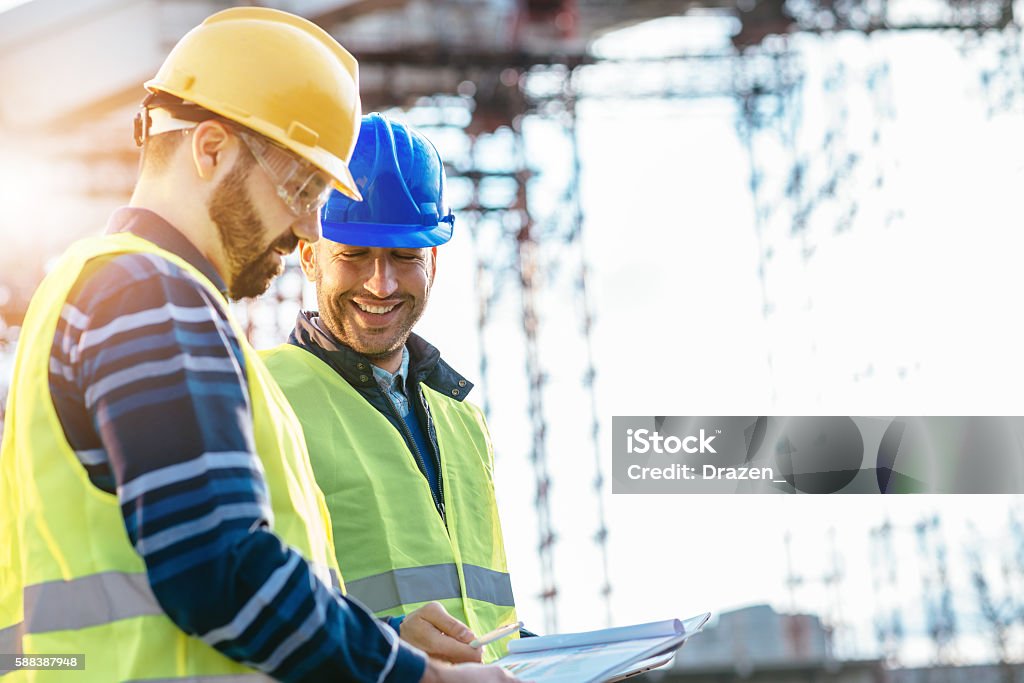 Good engineering team is guarantee to success. Two experts engineers in protective helmets and fluorescent vests showing the construction site and building activities after the successful project phase. Image taken with Nikon D800 and 85mm developed from RAW in XXXL size, in Novi Sad, Serbia, Central Europe, Europe Business Stock Photo