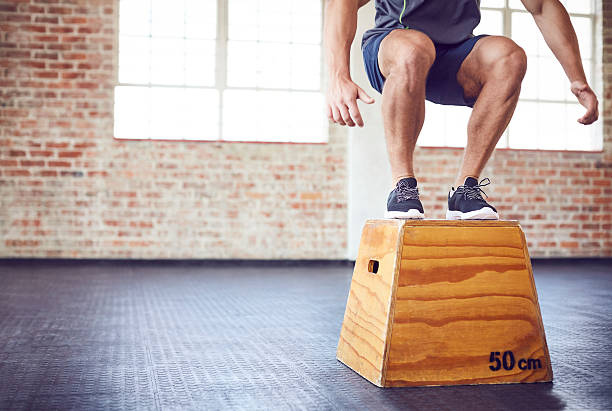 istock Male athlete landing while doing box jumping in gym 588388222