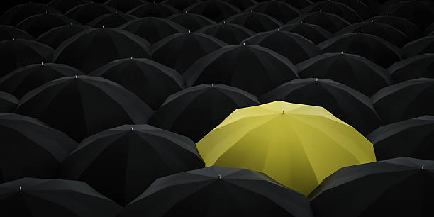 istock Unique yellow umbrella among many dark ones. 588388786