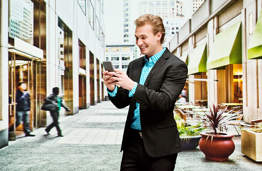Smiling businessman using phone outdoorshttp://www.twodozendesign.info/i/1.png