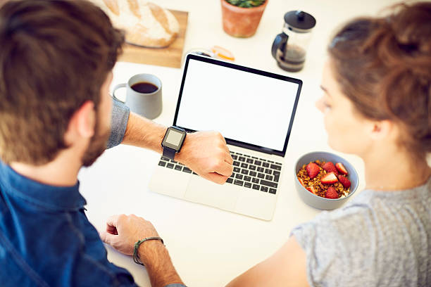 istock Young couple with smart watch and laptop at breakfast table 588391482