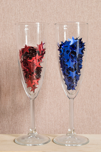 Champagne glasses full of red and blue star shaped confetti